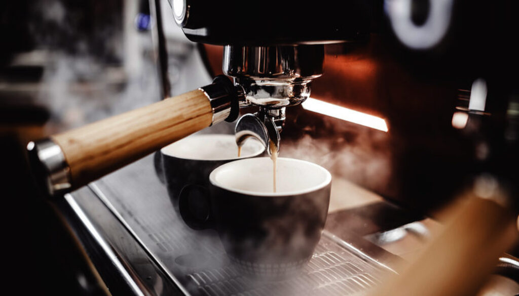 espresso poruing from coffee machine at cafe
