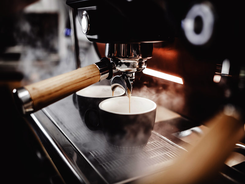 espresso poruing from coffee machine at cafe